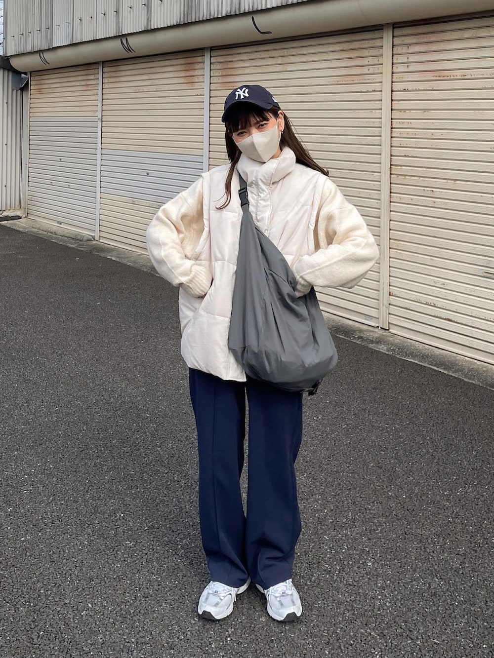 ホワイト系のダウンベスト、ホワイト系のニット/セーター、ブルー系のキャップを着用したレディースの春コーディネートの4枚目の写真