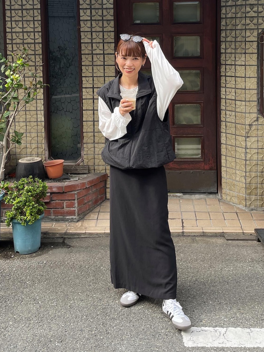 ブラック系のベスト、ホワイト系のTシャツ/カットソー、ブラック系のスカートを着用したレディースの秋コーディネートの2枚目の写真