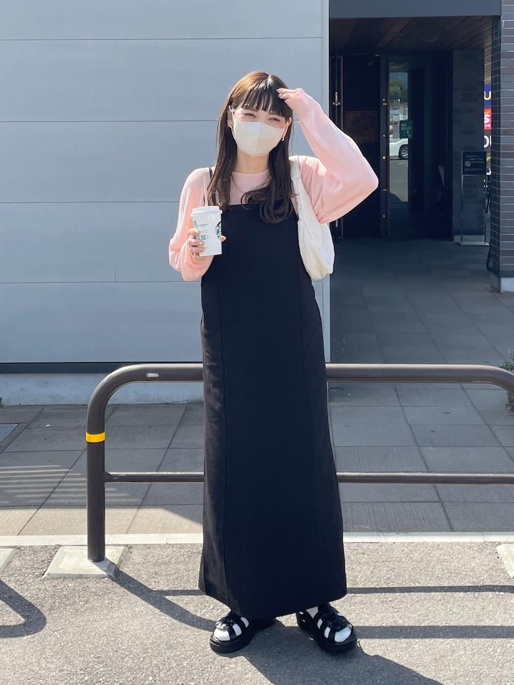 ブラック系のワンピース、ホワイト系のハンドバッグを着用したレディースの春コーディネートの2枚目の写真