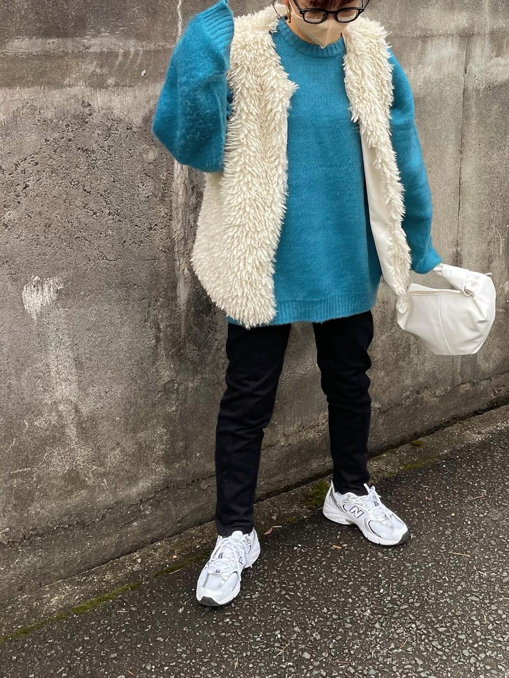 ブルー系のニット/セーター、ホワイト系のベスト、ブラック系のスウェットパンツを着用したレディースの冬コーディネートの2枚目の写真