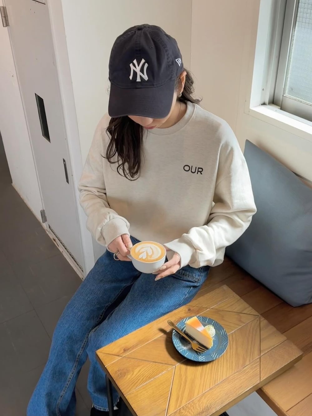 ホワイト系のスウェット、ブルー系のデニムパンツ、ブラック系のスニーカーを着用したレディースの春コーディネートの5枚目の写真