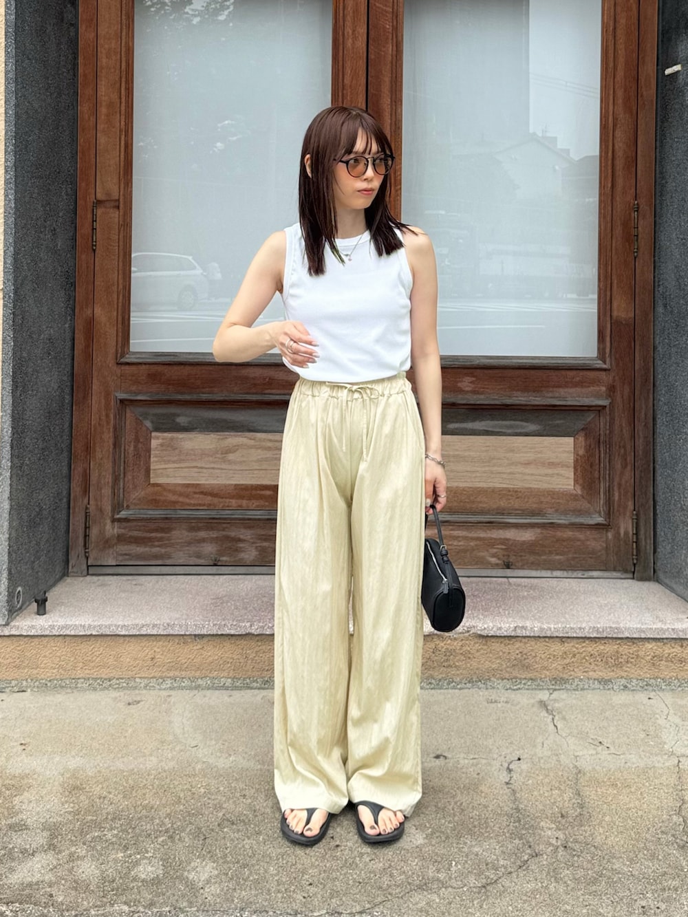 ホワイト系のタンクトップ、ベージュ系のその他パンツ、ブラック系のショルダーバッグを着用したレディースの夏コーディネートの2枚目の写真