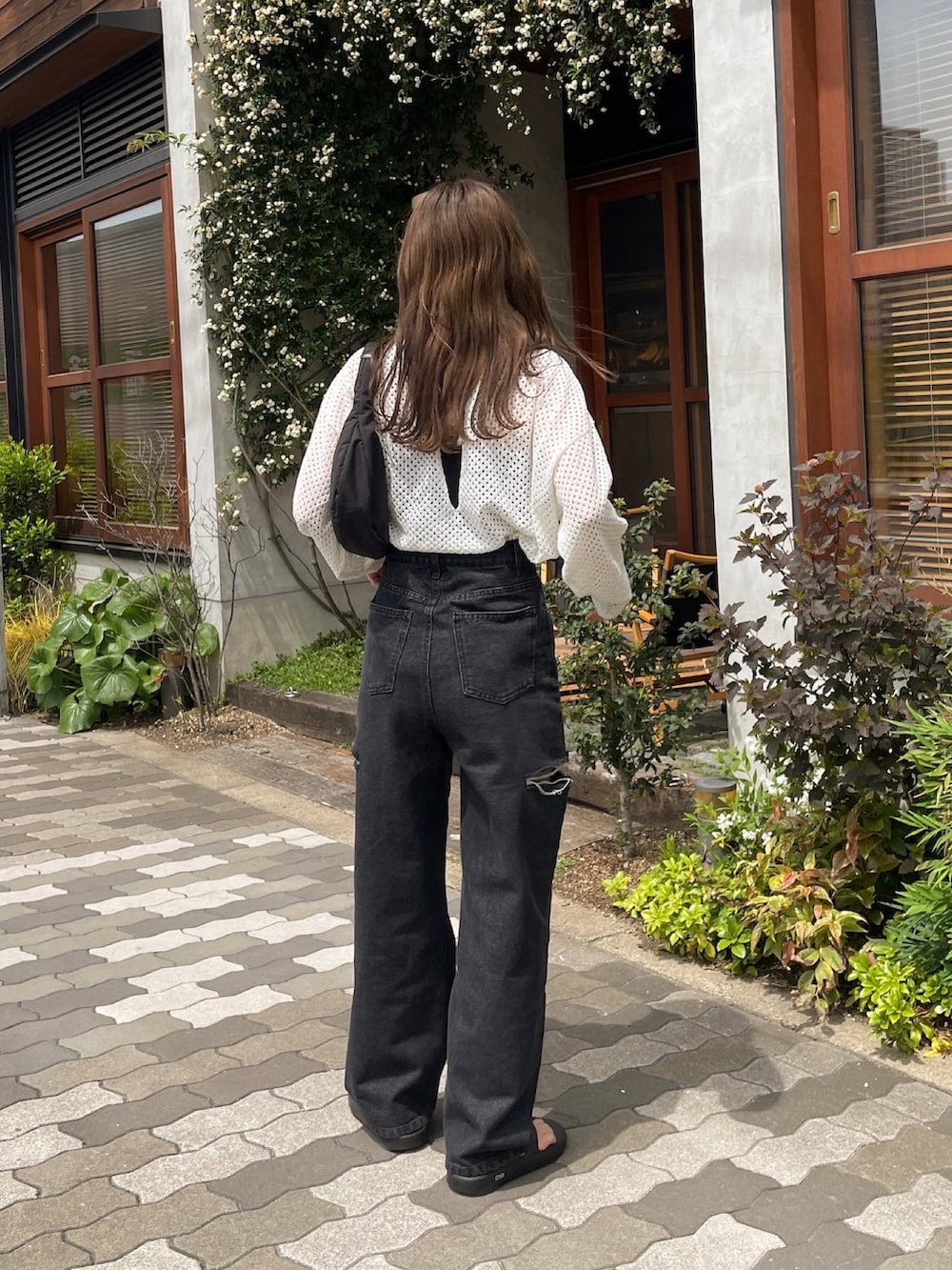 ホワイト系のニット/セーター、ブラック系のデニムパンツ、ブラック系のハンドバッグを着用したレディースの春コーディネートの3枚目の写真