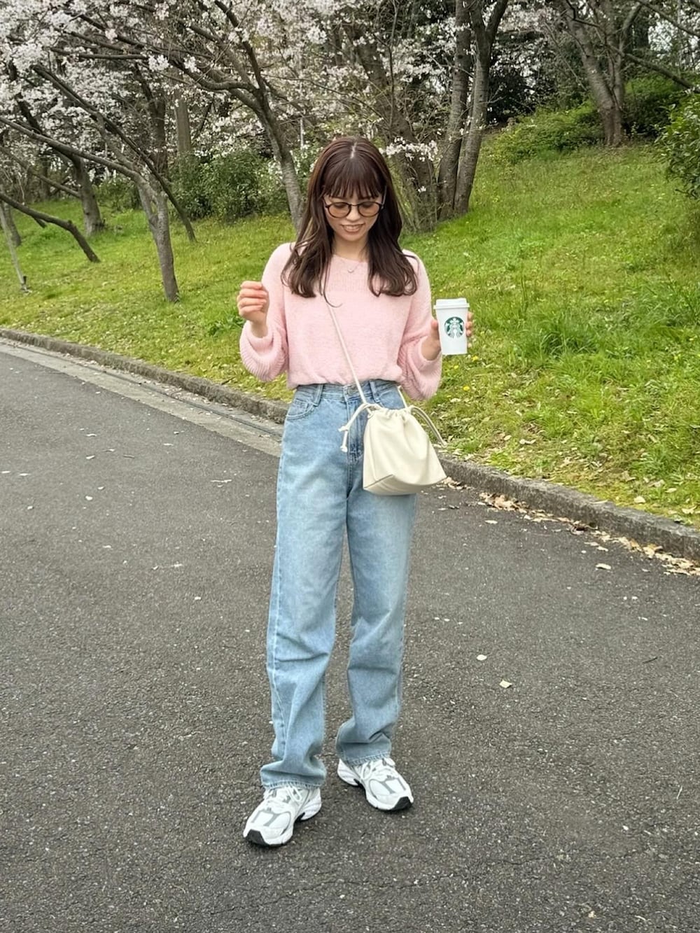 ブルー系のデニムパンツ、ピンク系のニット/セーター、ホワイト系のショルダーバッグを着用したレディースの春コーディネートの2枚目の写真
