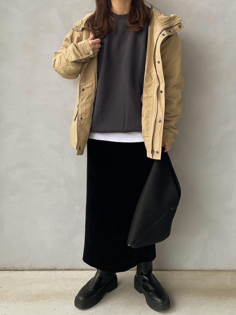 ベージュ系のマウンテンパーカー、ブラック系のTシャツ/カットソー、ブラック系のスカートを着用したレディースの冬コーディネートの2枚目の写真