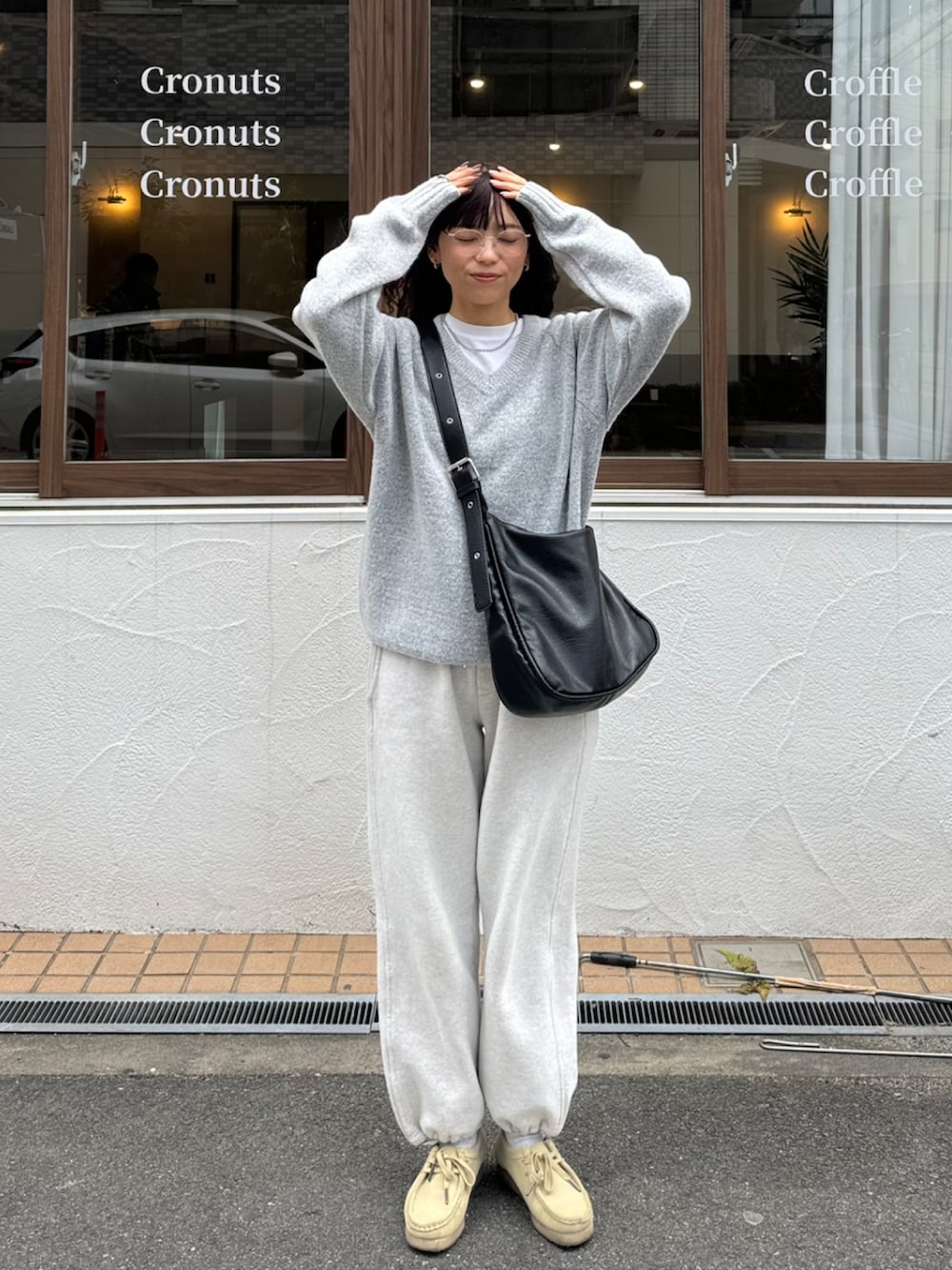 グレー系のニット/セーター、ベージュ系のスウェットパンツ、ブラック系のショルダーバッグを着用したレディースの春コーディネートの2枚目の写真