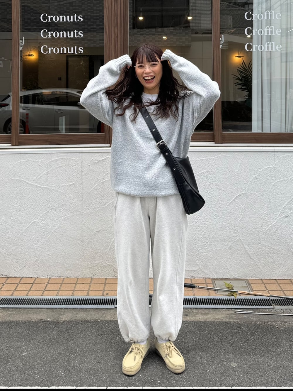 グレー系のニット/セーター、ベージュ系のスウェットパンツ、ブラック系のショルダーバッグを着用したレディースの春コーディネートの3枚目の写真