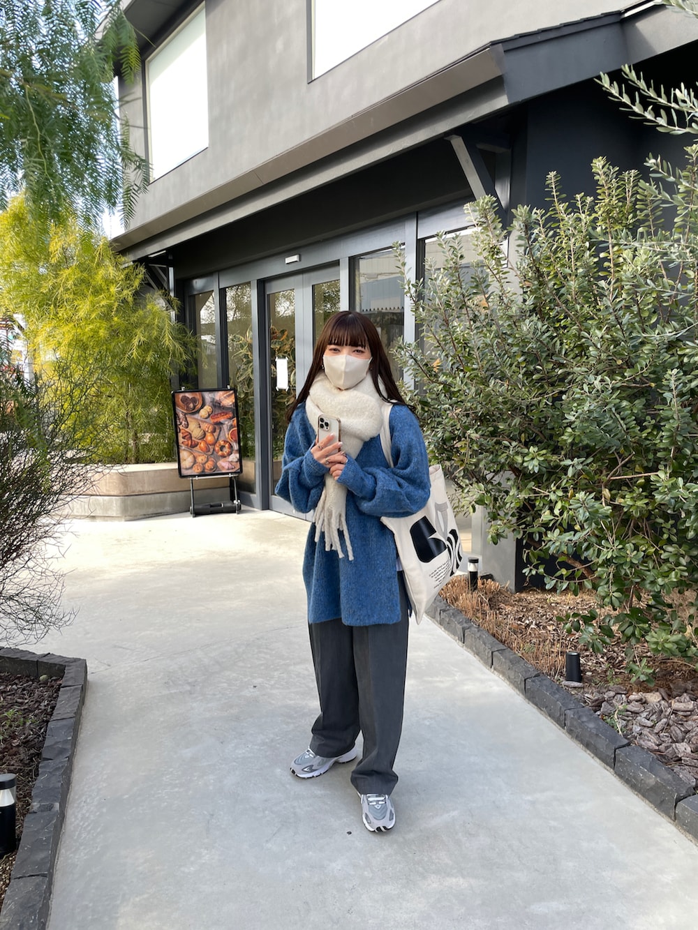 ブルー系のニット/セーター、ベージュ系のスニーカー、ホワイト系のマフラーを着用したレディースの冬コーディネートの3枚目の写真