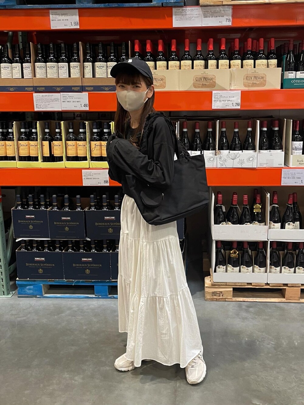 ホワイト系のスカート、ブラック系のトートバッグ、ブラック系のキャップを着用したレディースの夏コーディネートの3枚目の写真