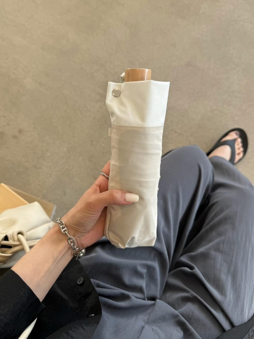 ホワイト系のショルダーバッグ、ベージュ系の折りたたみ傘を着用したレディースの春コーディネートの3枚目の写真