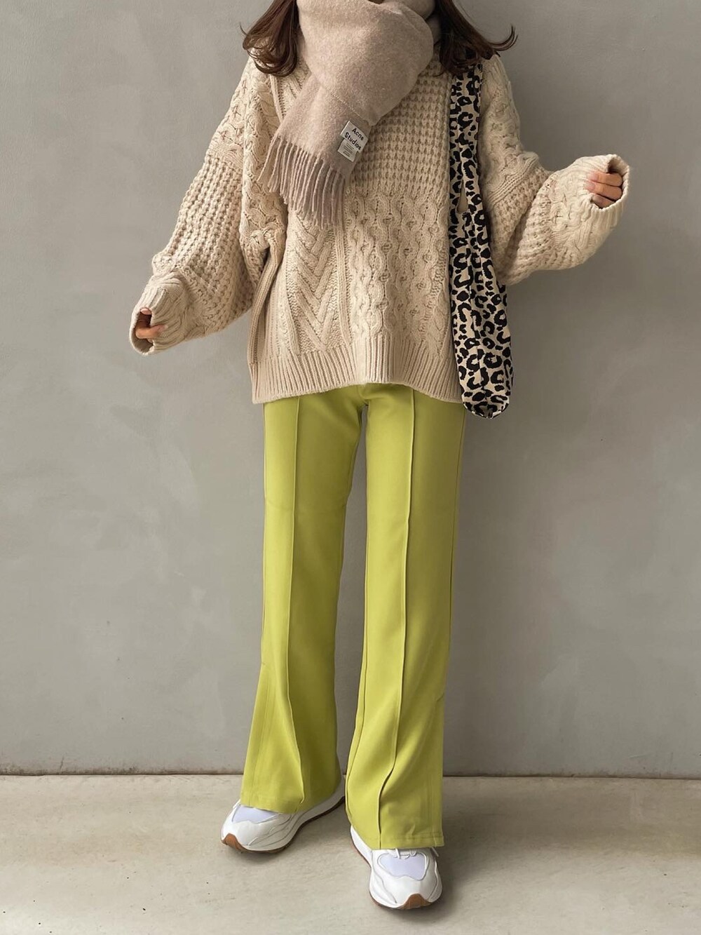 グリーン系のスラックス、ベージュ系のトートバッグ、ホワイト系のスニーカーを着用したレディースの冬コーディネートの2枚目の写真