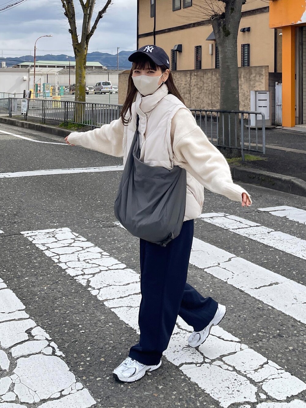 ホワイト系のダウンベスト、ホワイト系のニット/セーター、ブルー系のキャップを着用したレディースの春コーディネートの2枚目の写真