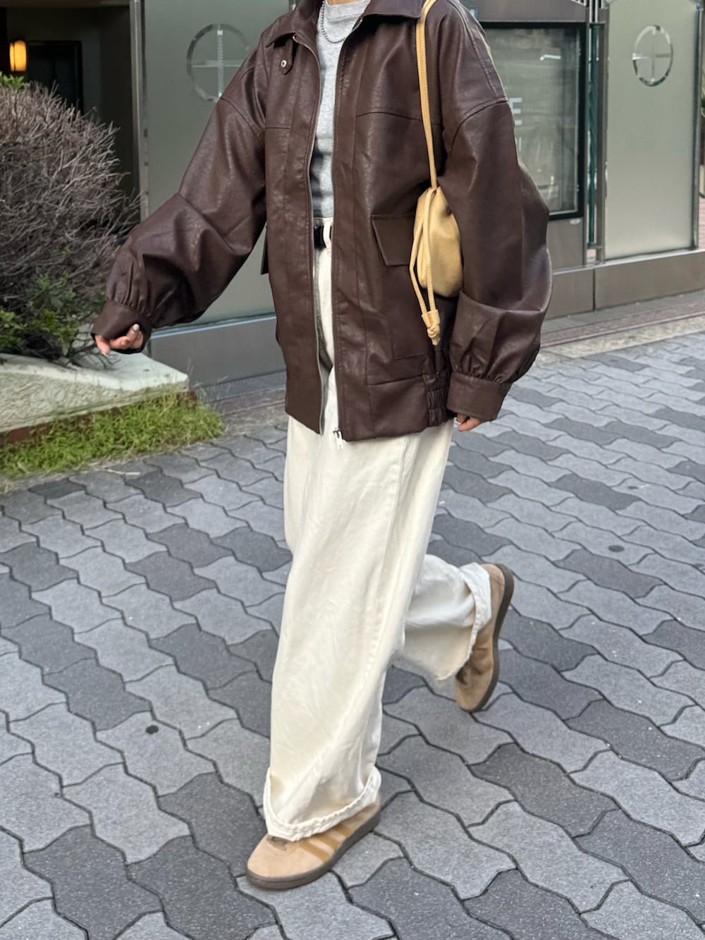 ブラウン系のブルゾン、ホワイト系のデニムパンツ、ベージュ系のスニーカーを着用したレディースの秋コーディネートの2枚目の写真