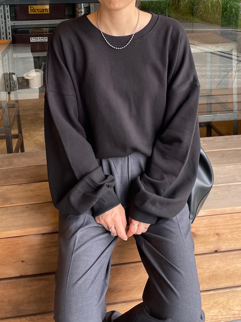 ブラック系のスウェット、ブラック系のトートバッグ、ホワイト系のスニーカーを着用したレディースの秋コーディネートの4枚目の写真