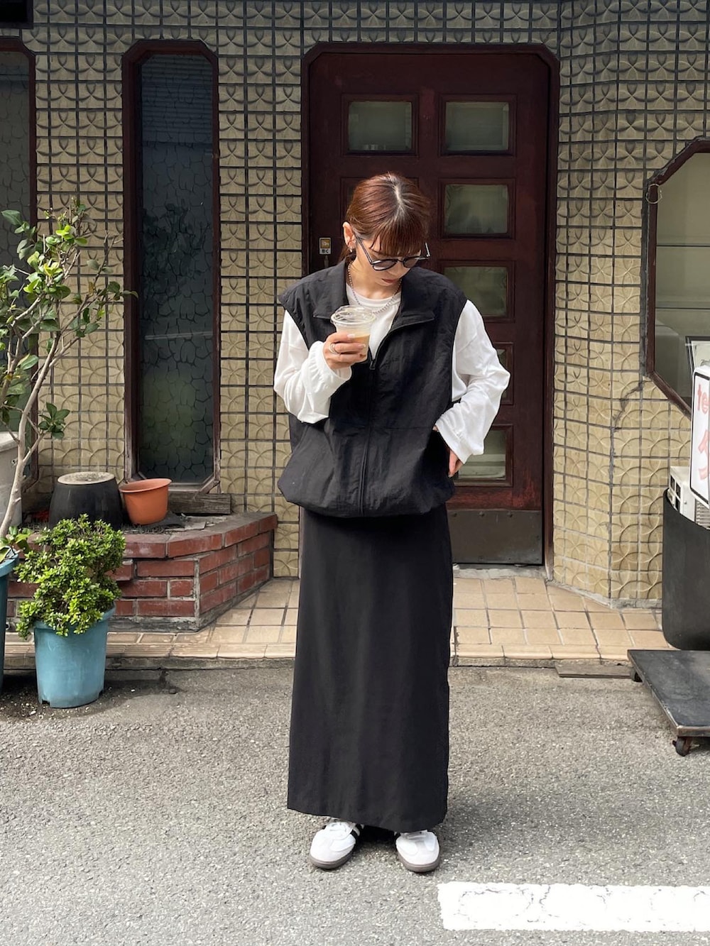 ブラック系のベスト、ホワイト系のTシャツ/カットソー、ブラック系のスカートを着用したレディースの秋コーディネートの4枚目の写真
