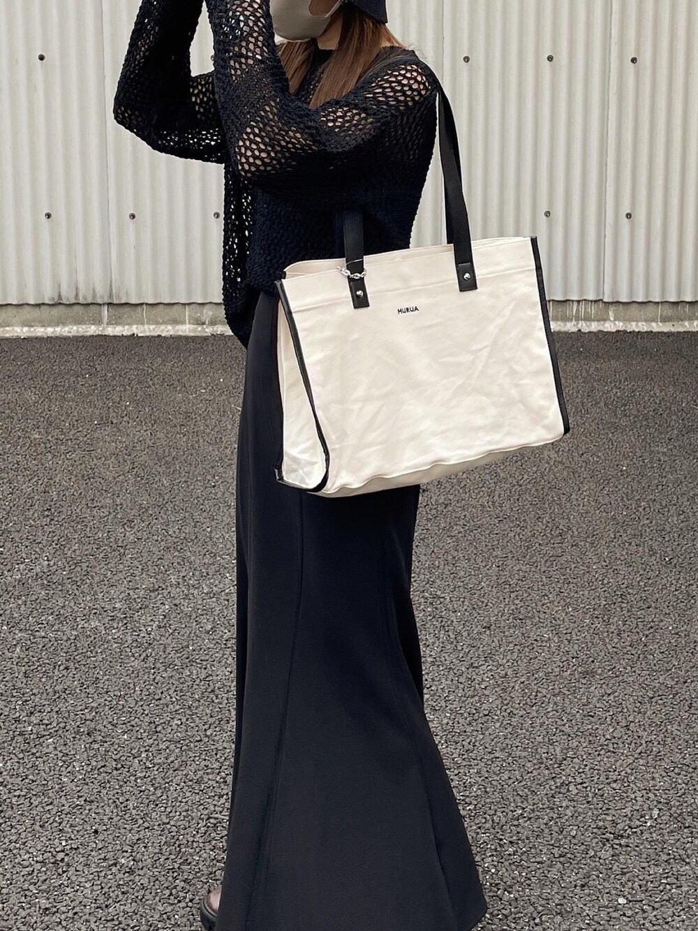 ブラック系のニット/セーター、ホワイト系のトートバッグ、ブラウン系のブーツを着用したレディースの秋コーディネートの4枚目の写真