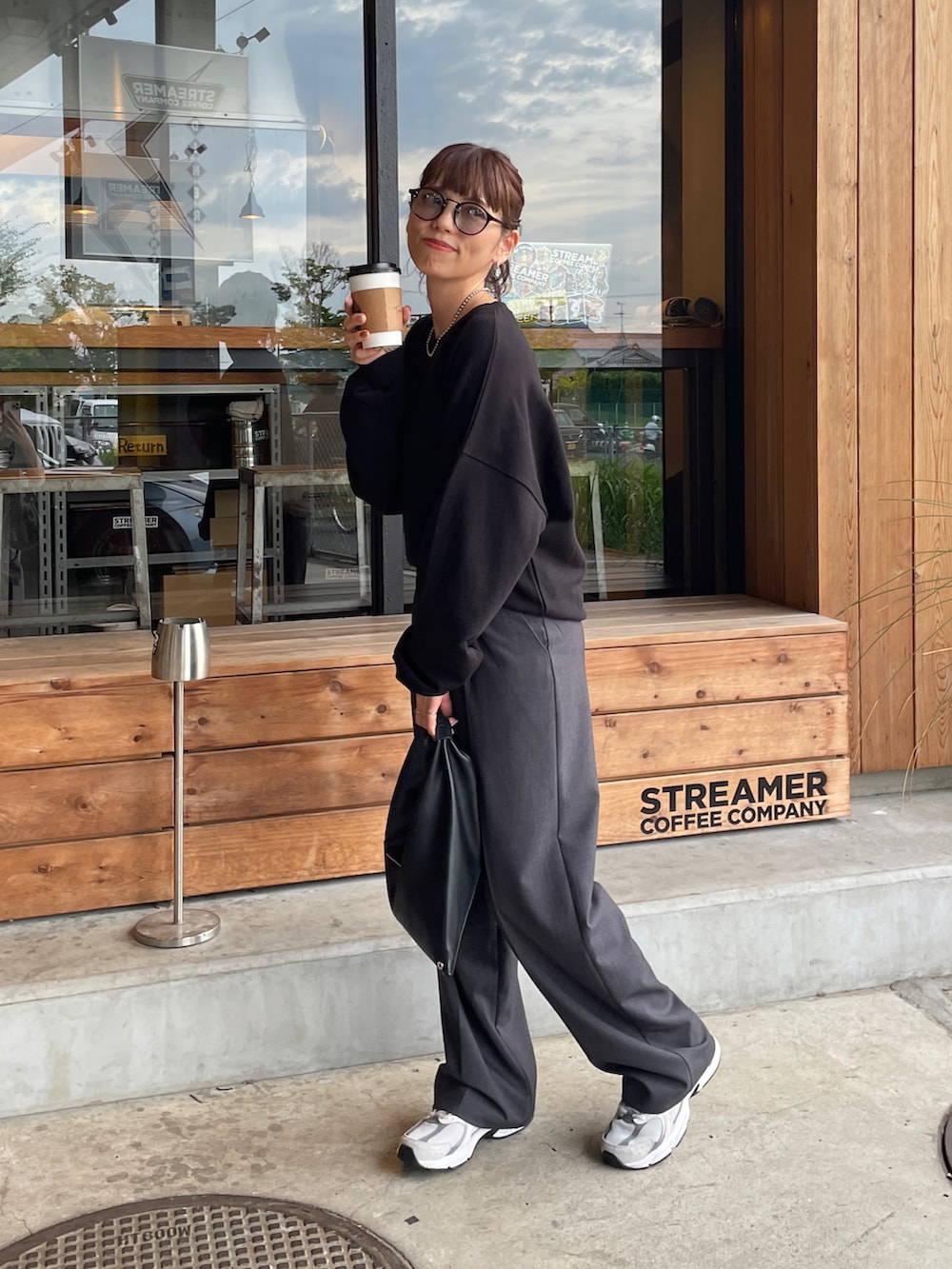 ブラック系のスウェット、ブラック系のトートバッグ、ホワイト系のスニーカーを着用したレディースの秋コーディネートの5枚目の写真