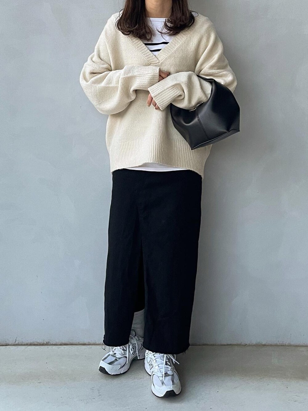 ホワイト系のニット/セーター、ブラック系のスカート、ブラック系のハンドバッグを着用したレディースの冬コーディネートの2枚目の写真