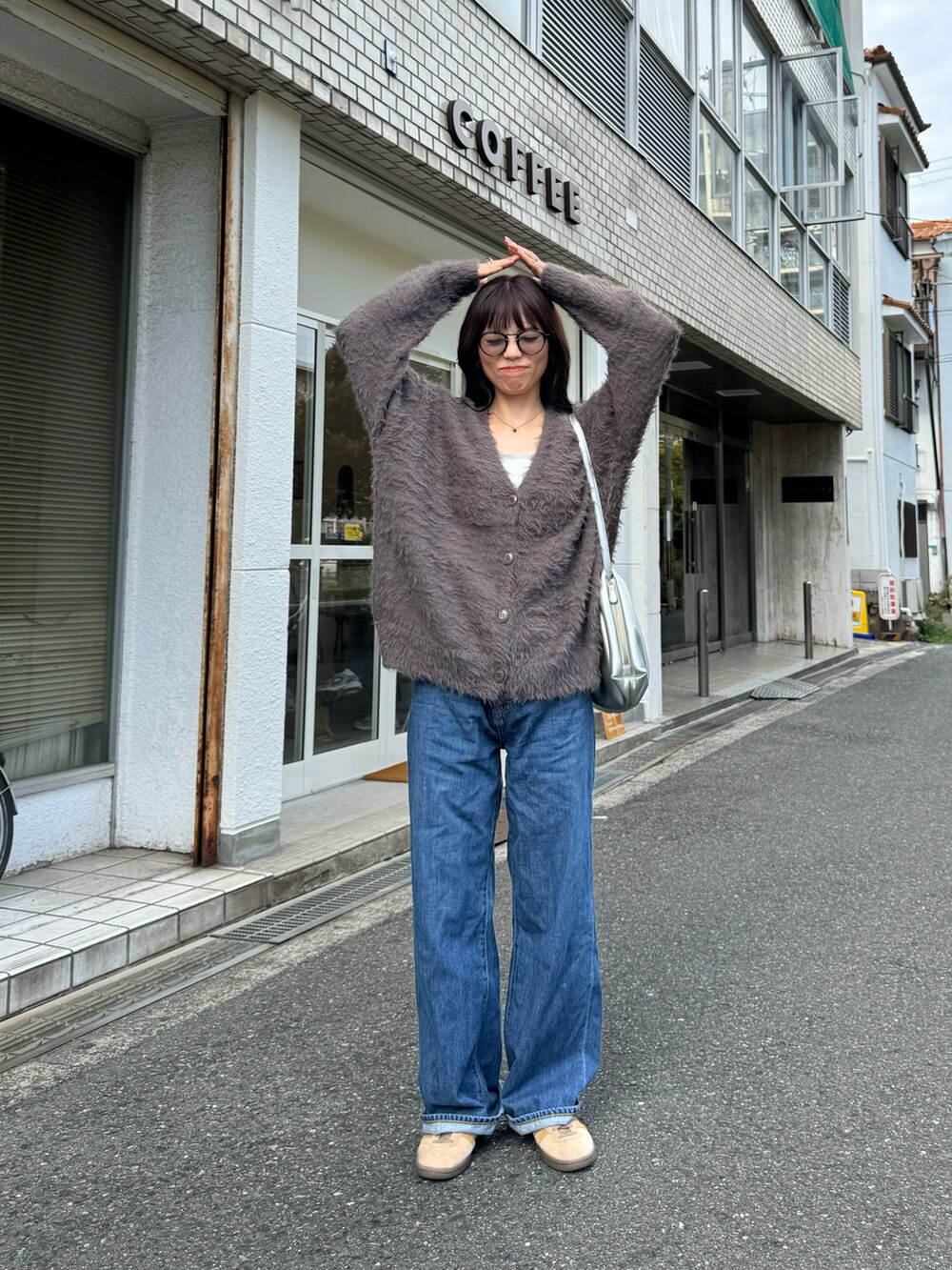 グレー系のカーディガン/ボレロ、ブルー系のデニムパンツ、ベージュ系のスニーカーを着用したレディースの秋コーディネートの2枚目の写真