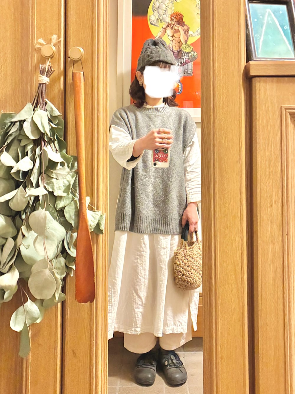 グレー系のベスト、ホワイト系のワンピース、ベージュ系のかごバッグを着用したレディースの冬コーディネートの2枚目の写真