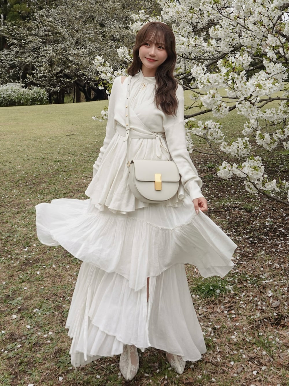 ホワイト系のスカート、ホワイト系のニット/セーター、ホワイト系のバッグを着用したレディースの春コーディネートの3枚目の写真