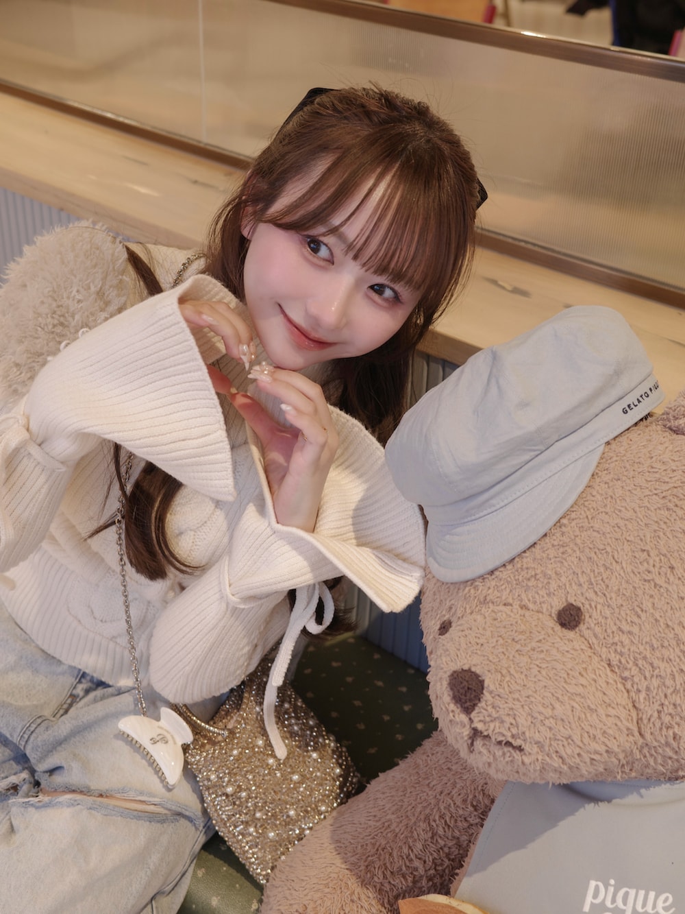 ブルー系のデニムパンツ、ホワイト系のトップス、ゴールド系のバッグを着用したレディースの冬コーディネートの4枚目の写真