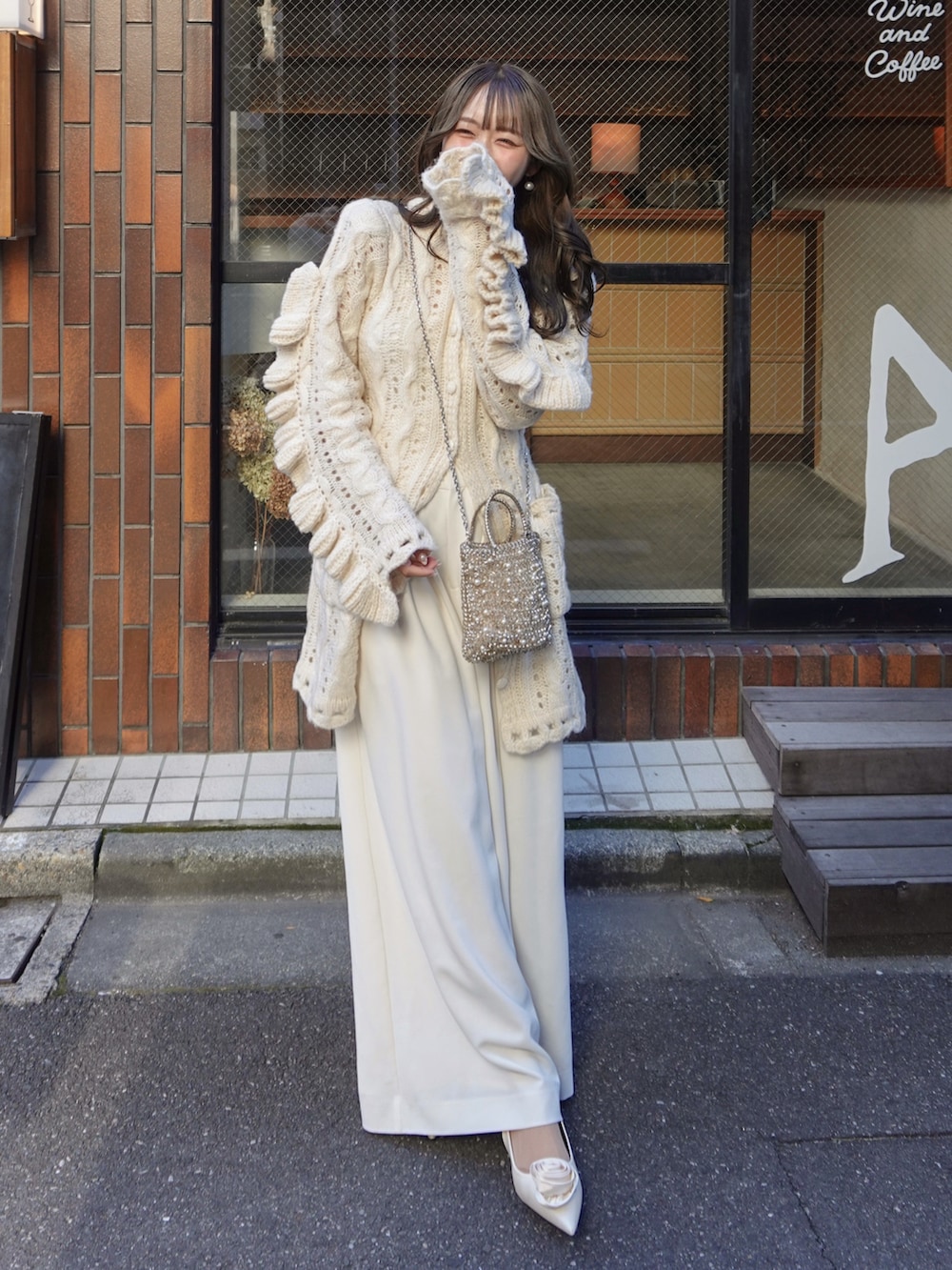 ホワイト系のトップス、ゴールド系のバッグ、ホワイト系のスラックスを着用したレディースの冬コーディネートの2枚目の写真