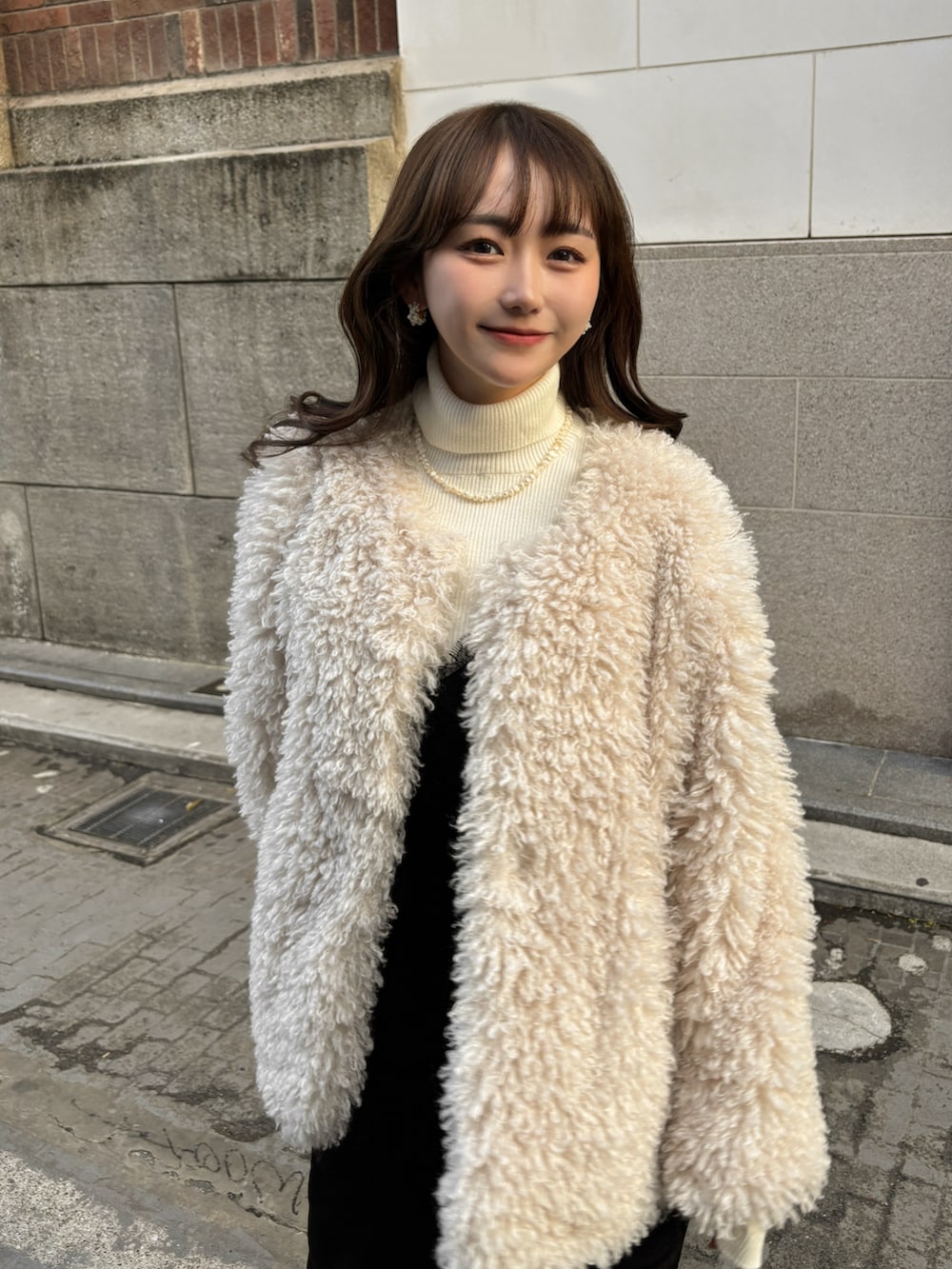 ホワイト系のその他アウター、ホワイト系のニット/セーター、ブラック系のワンピースを着用したレディースの冬コーディネートの4枚目の写真