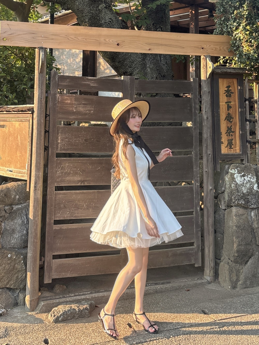 ブラック系のサンダル、ホワイト系のワンピース/ドレス、ブラック系のバッグを着用したレディースの夏コーディネートの5枚目の写真