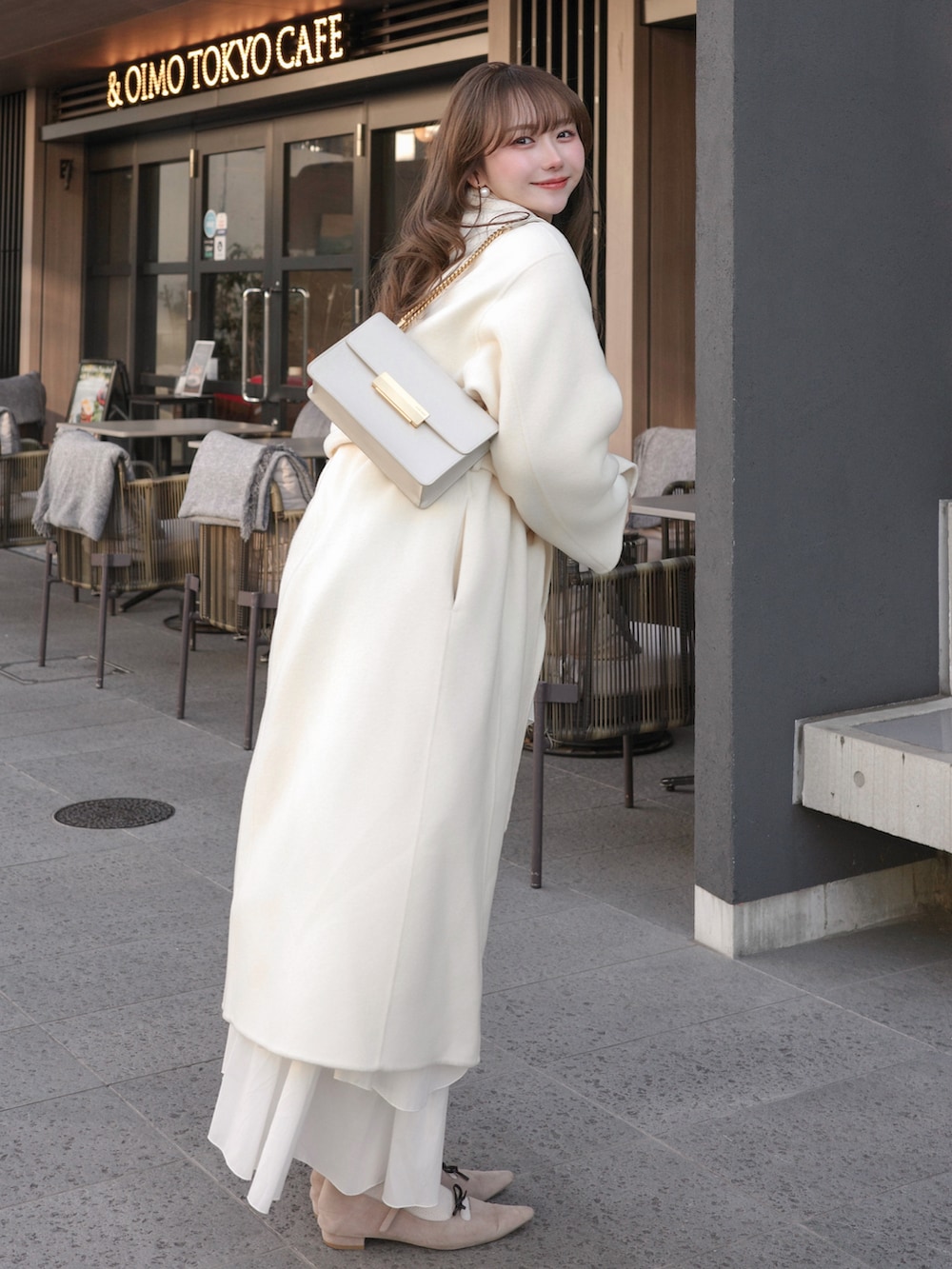 ホワイト系のチェスターコート、ベージュ系のトップス、ホワイト系のバッグを着用したレディースの冬コーディネートの2枚目の写真