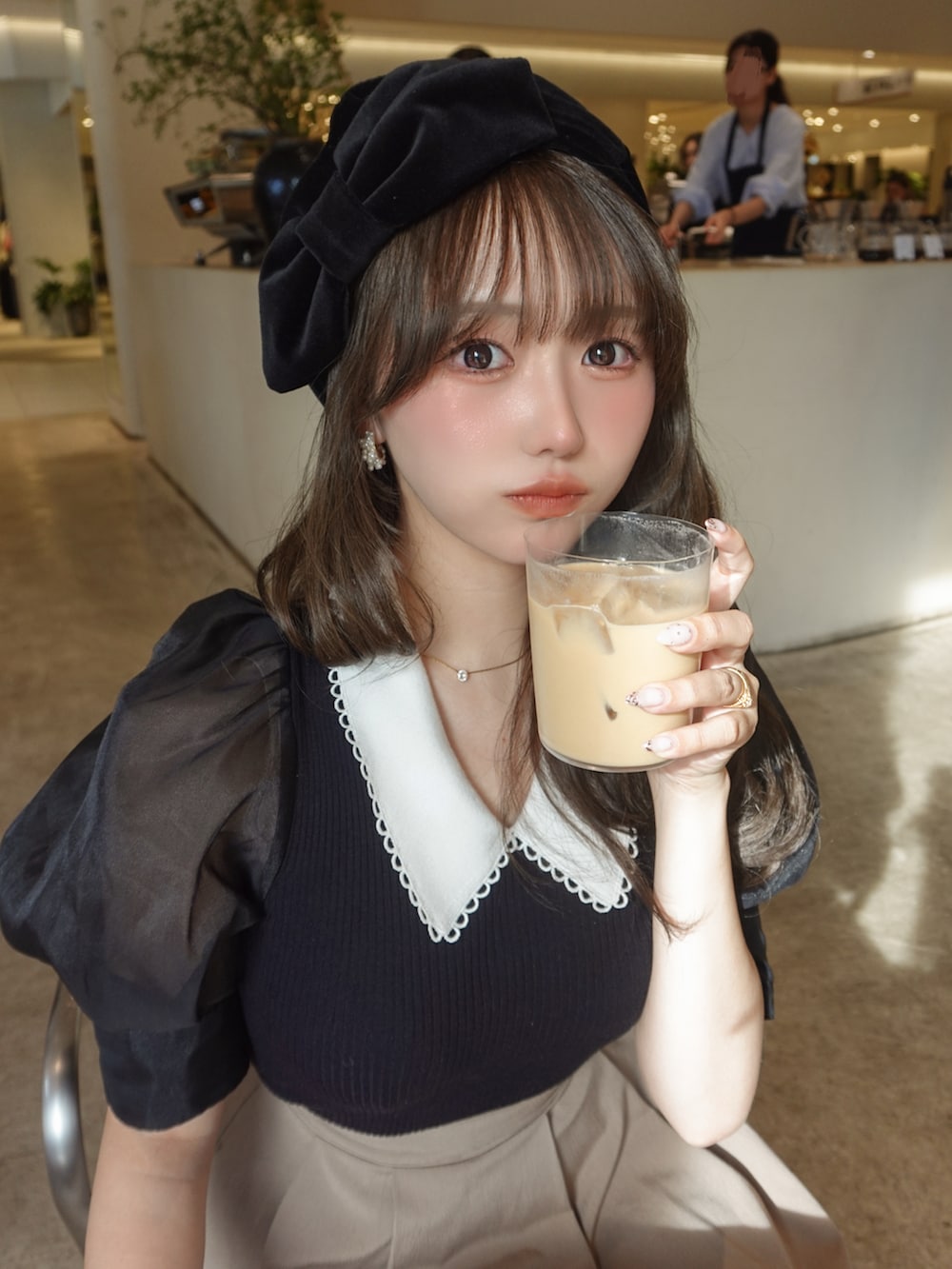 ベージュ系のスカート、ホワイト系のサンダル、ブラック系のニット/セーターを着用したレディースの夏コーディネートの3枚目の写真