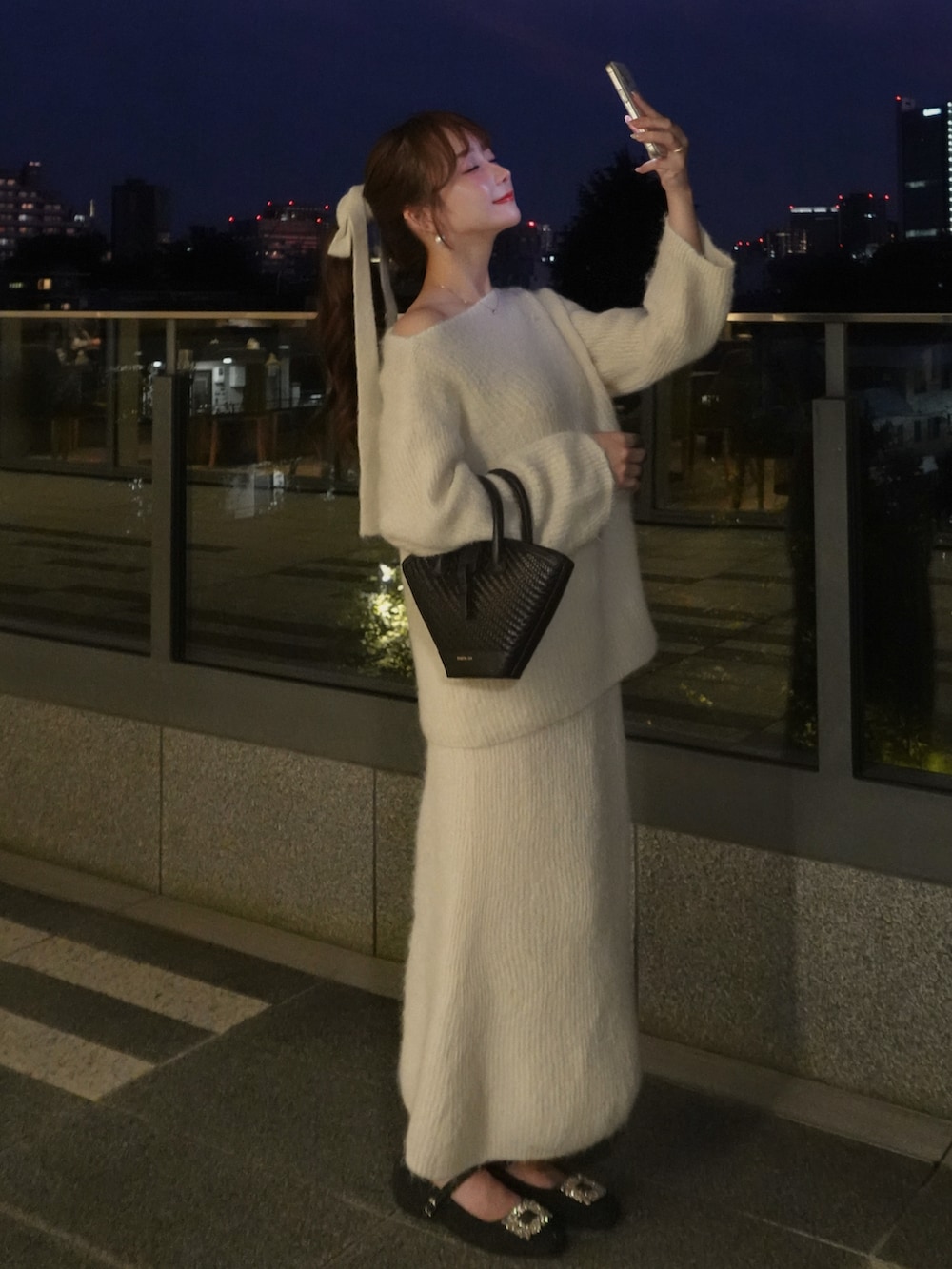 ホワイト系のセットアップ、ホワイト系のスカート、ブラック系のバッグを着用したレディースの冬コーディネートの2枚目の写真