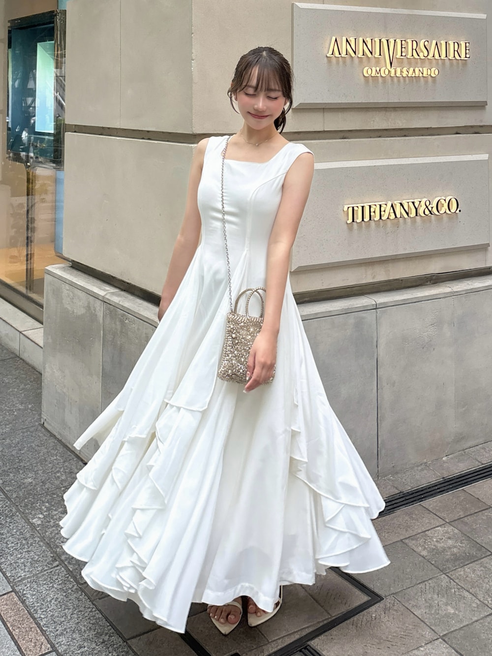 ホワイト系のワンピース/ドレス、ゴールド系のバッグ、ホワイト系のサンダルを着用したレディースの夏コーディネートの2枚目の写真