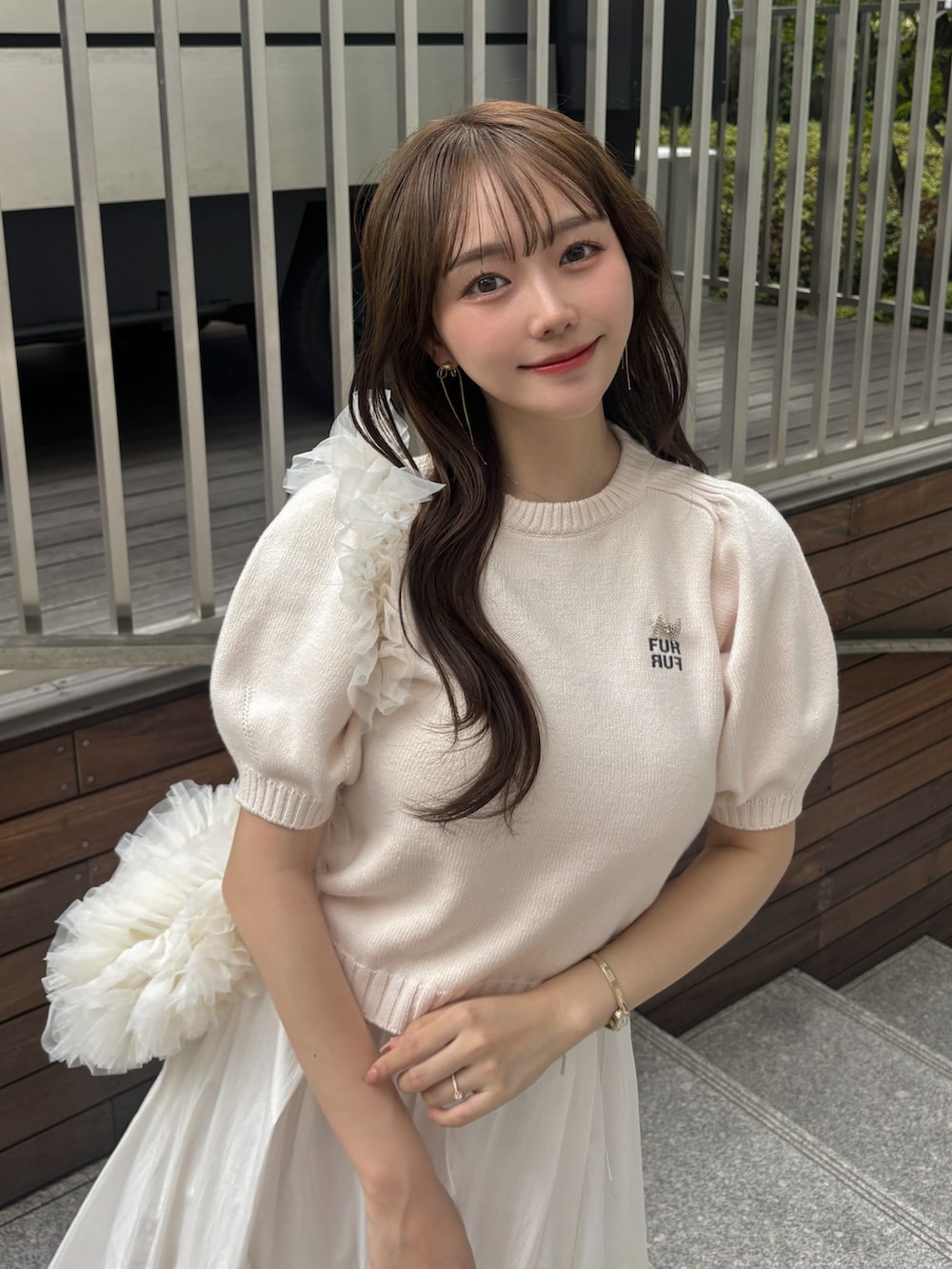 ホワイト系のスカート、ピンク系のトップス、ホワイト系のハンドバッグを着用したレディースの夏コーディネートの3枚目の写真