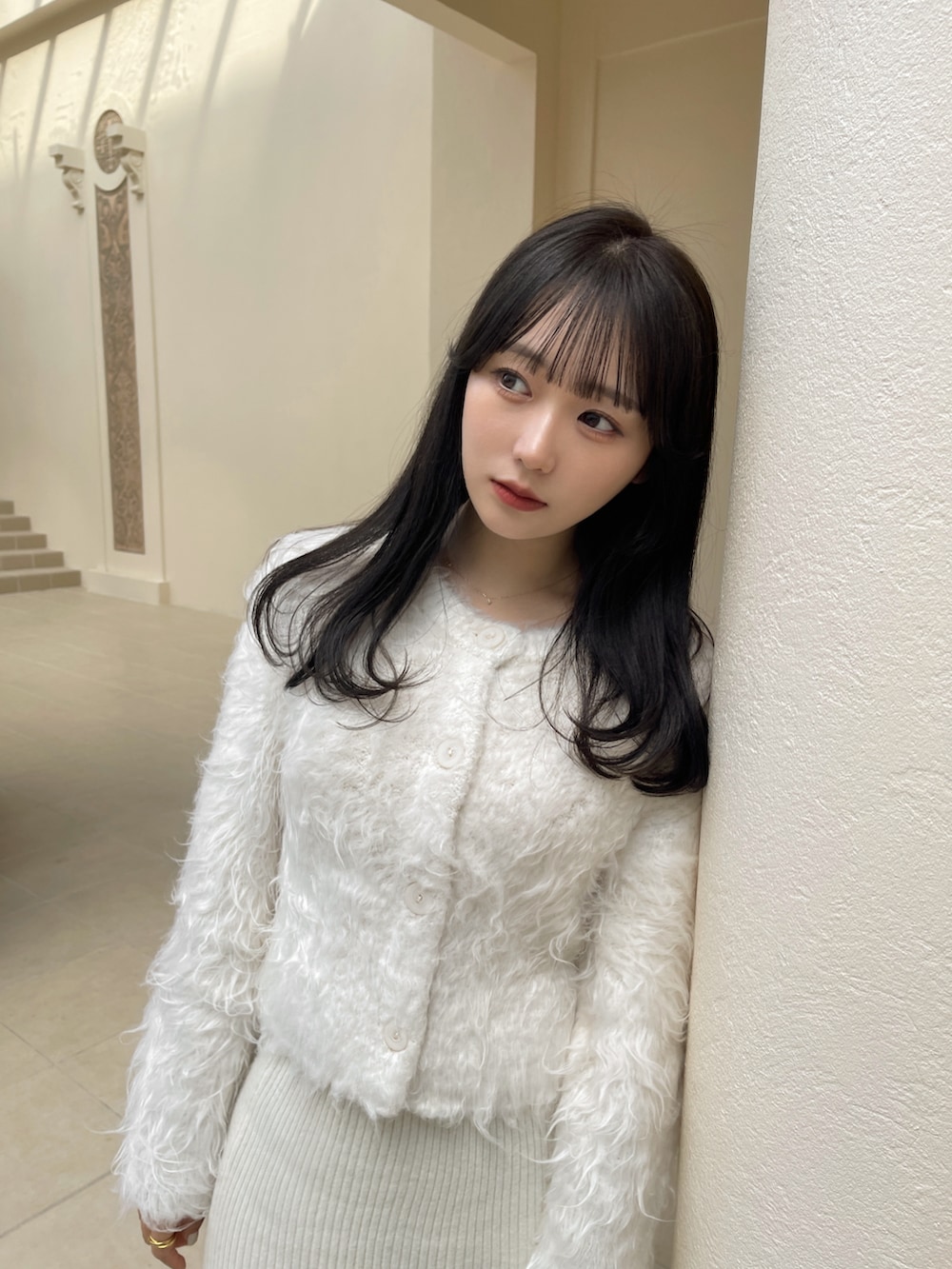 ホワイト系のスカート、ホワイト系のカーディガン/ボレロ、ブラウン系のバッグを着用したレディースの秋コーディネートの2枚目の写真