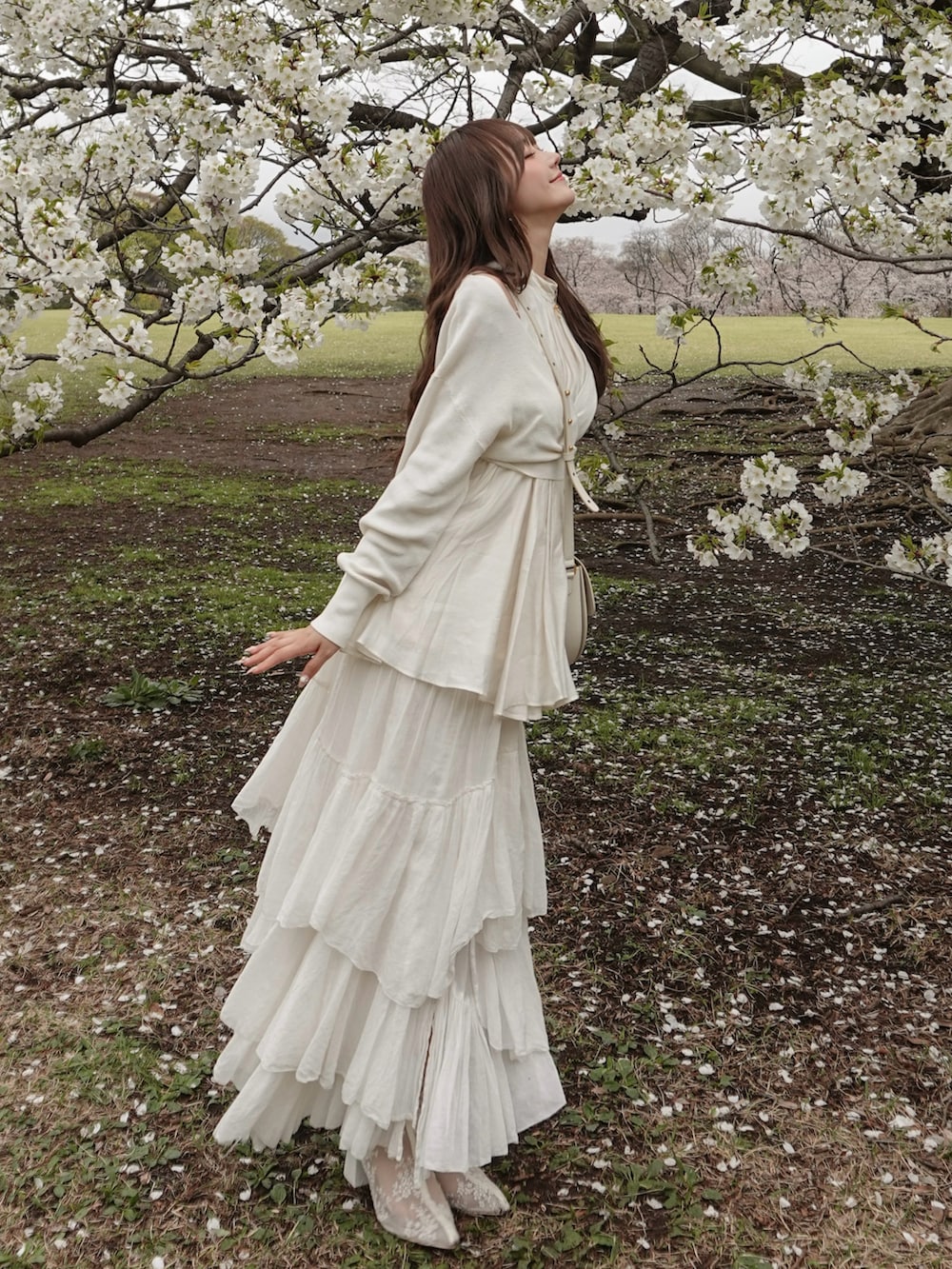 ホワイト系のスカート、ホワイト系のニット/セーター、ホワイト系のバッグを着用したレディースの春コーディネートの2枚目の写真