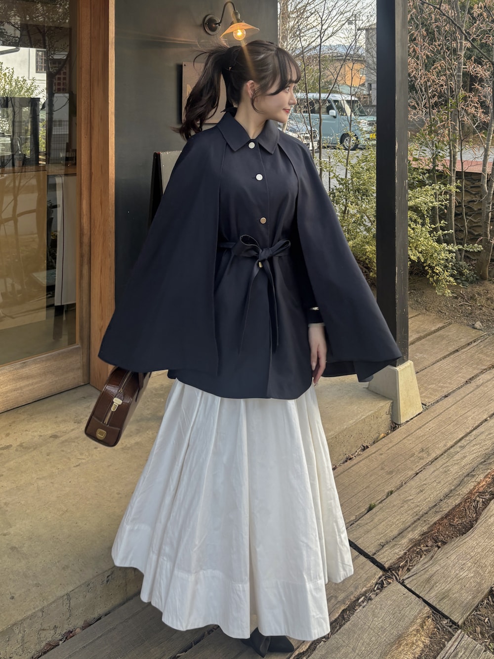 ブルー系のその他アウター、ホワイト系のスカート、ブラウン系のバッグを着用したレディースの春コーディネートの2枚目の写真