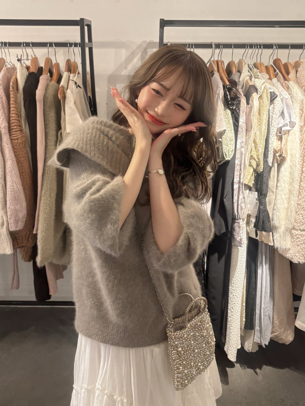 ゴールド系のバッグ、ブラウン系のニット/セーター、ホワイト系のスカートを着用したレディースの秋コーディネートの3枚目の写真