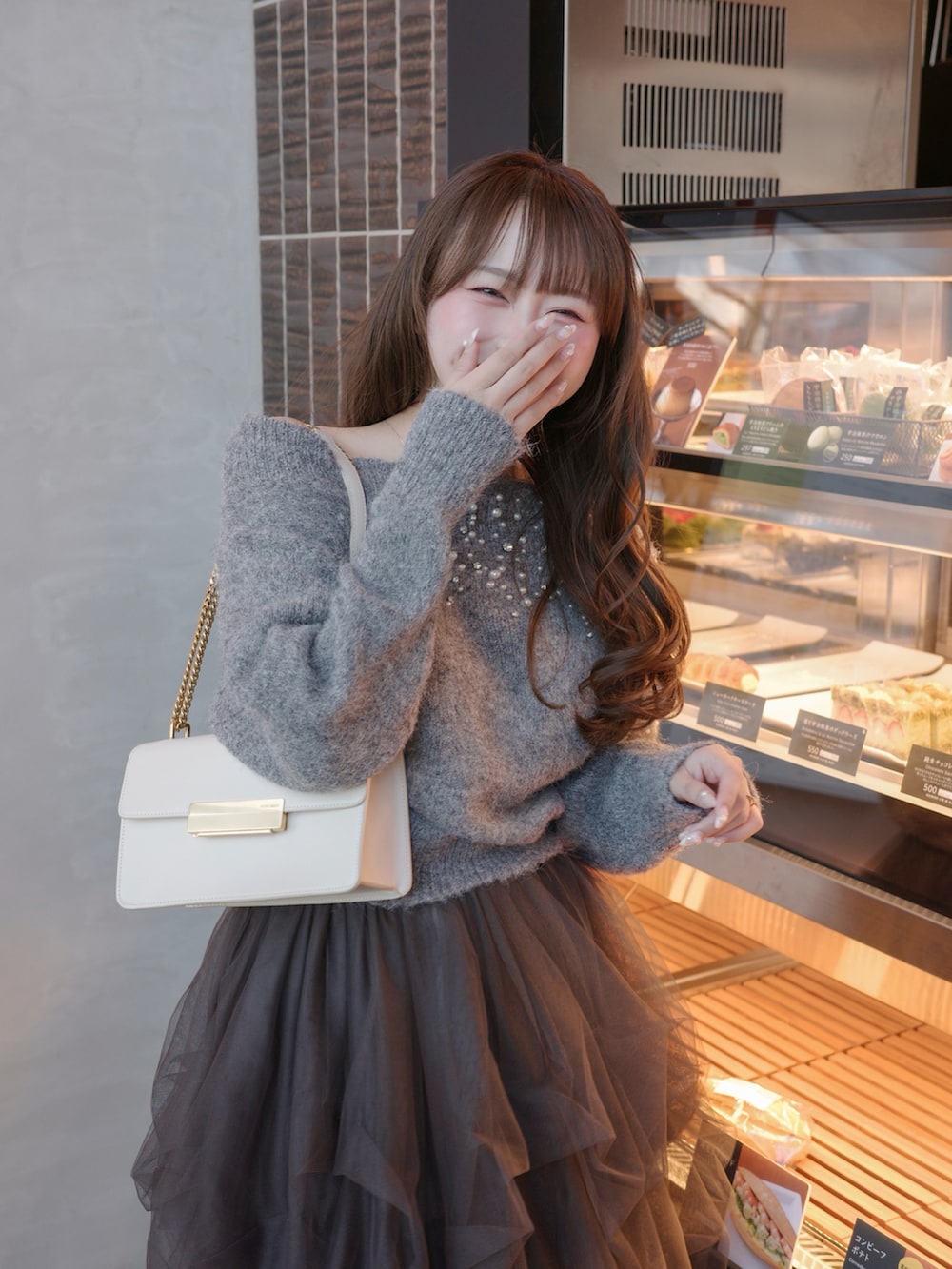 グレー系のパンプス、グレー系のニット/セーター、グレー系のスカートを着用したレディースの春コーディネートの4枚目の写真