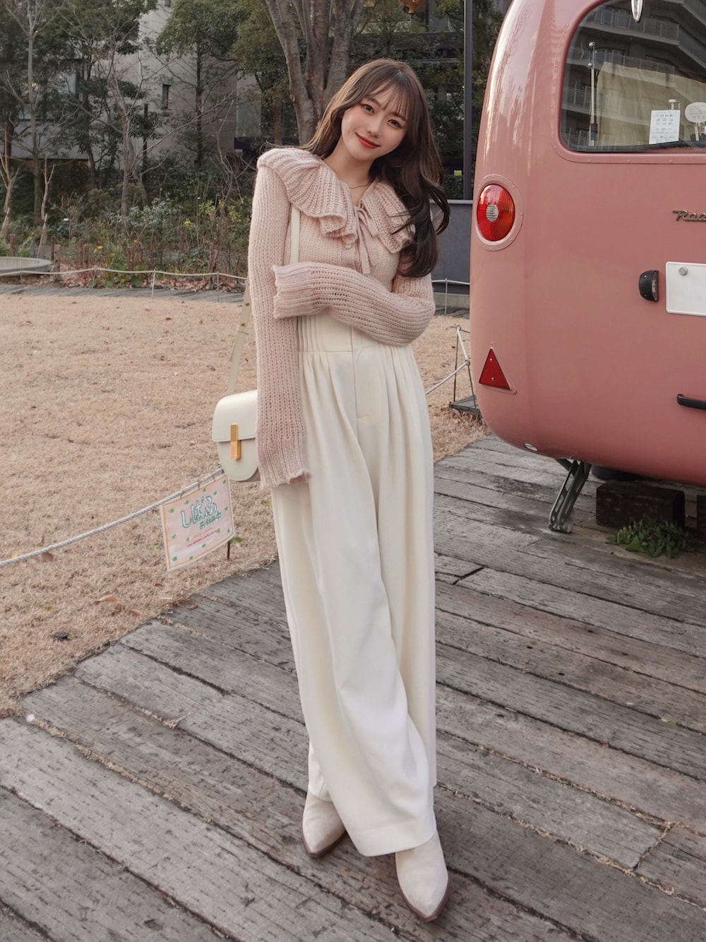 ベージュ系のブーツ、ピンク系のニット/セーター、ホワイト系のスラックスを着用したレディースの春コーディネートの2枚目の写真