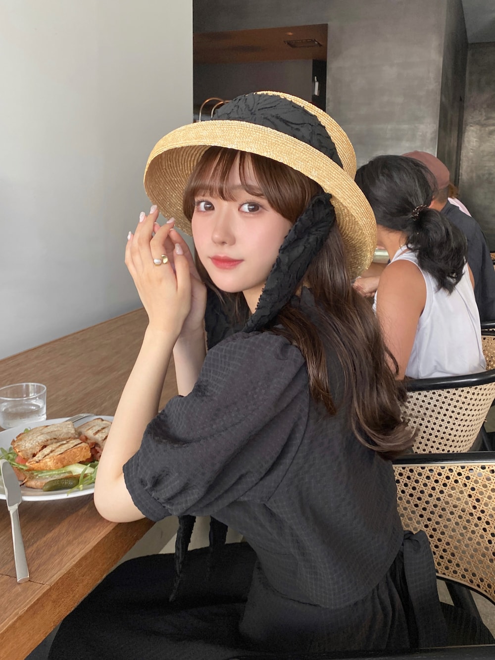 ベージュ系のバッグ、ホワイト系のサンダル、ブラック系のワンピースを着用したレディースの夏コーディネートの2枚目の写真