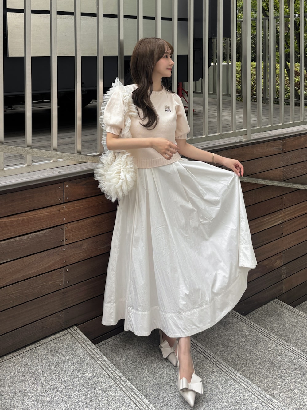 ホワイト系のスカート、ピンク系のトップス、ホワイト系のハンドバッグを着用したレディースの夏コーディネートの2枚目の写真