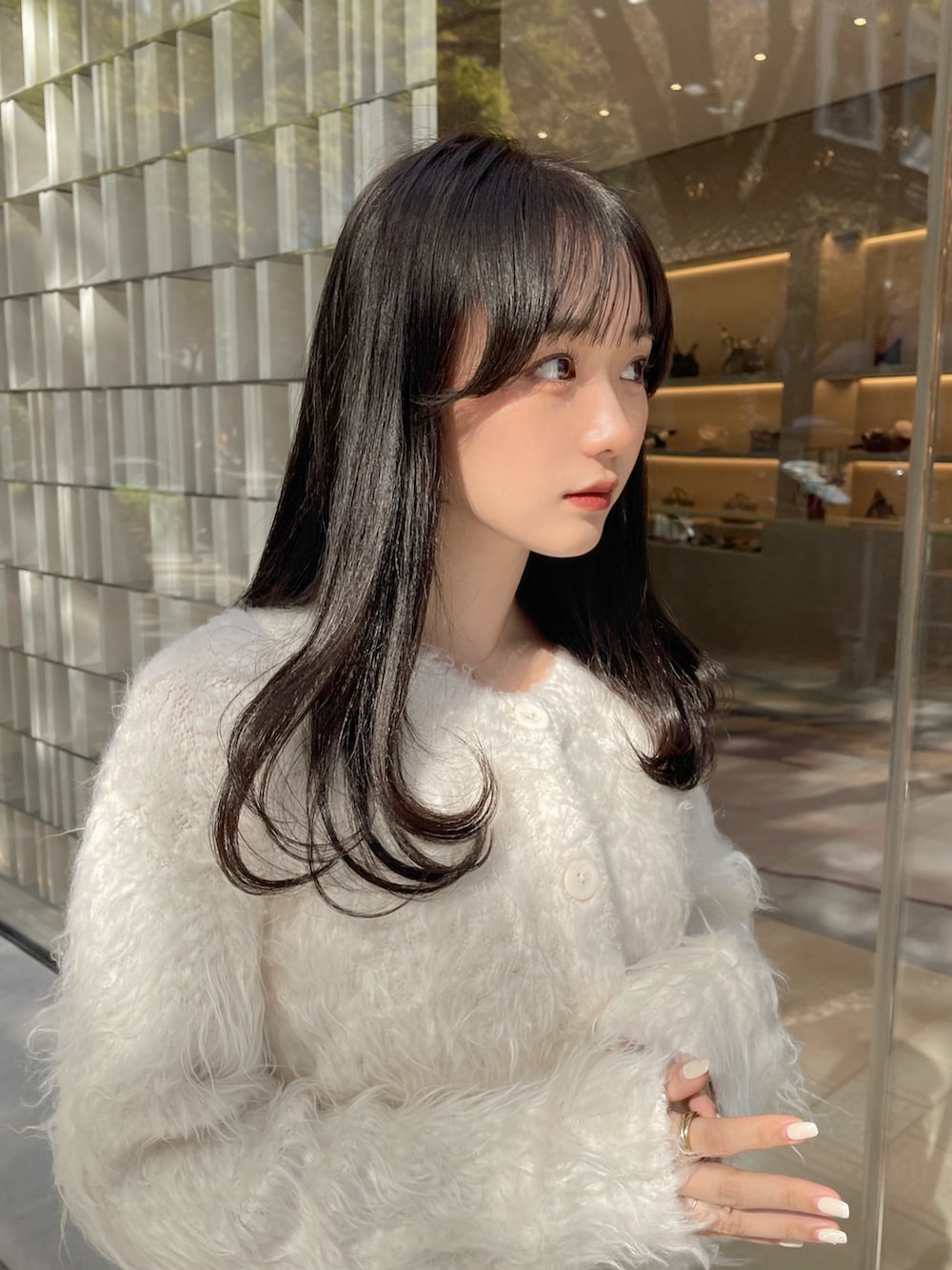 ホワイト系のスカート、ホワイト系のカーディガン/ボレロ、ブラウン系のバッグを着用したレディースの秋コーディネートの4枚目の写真