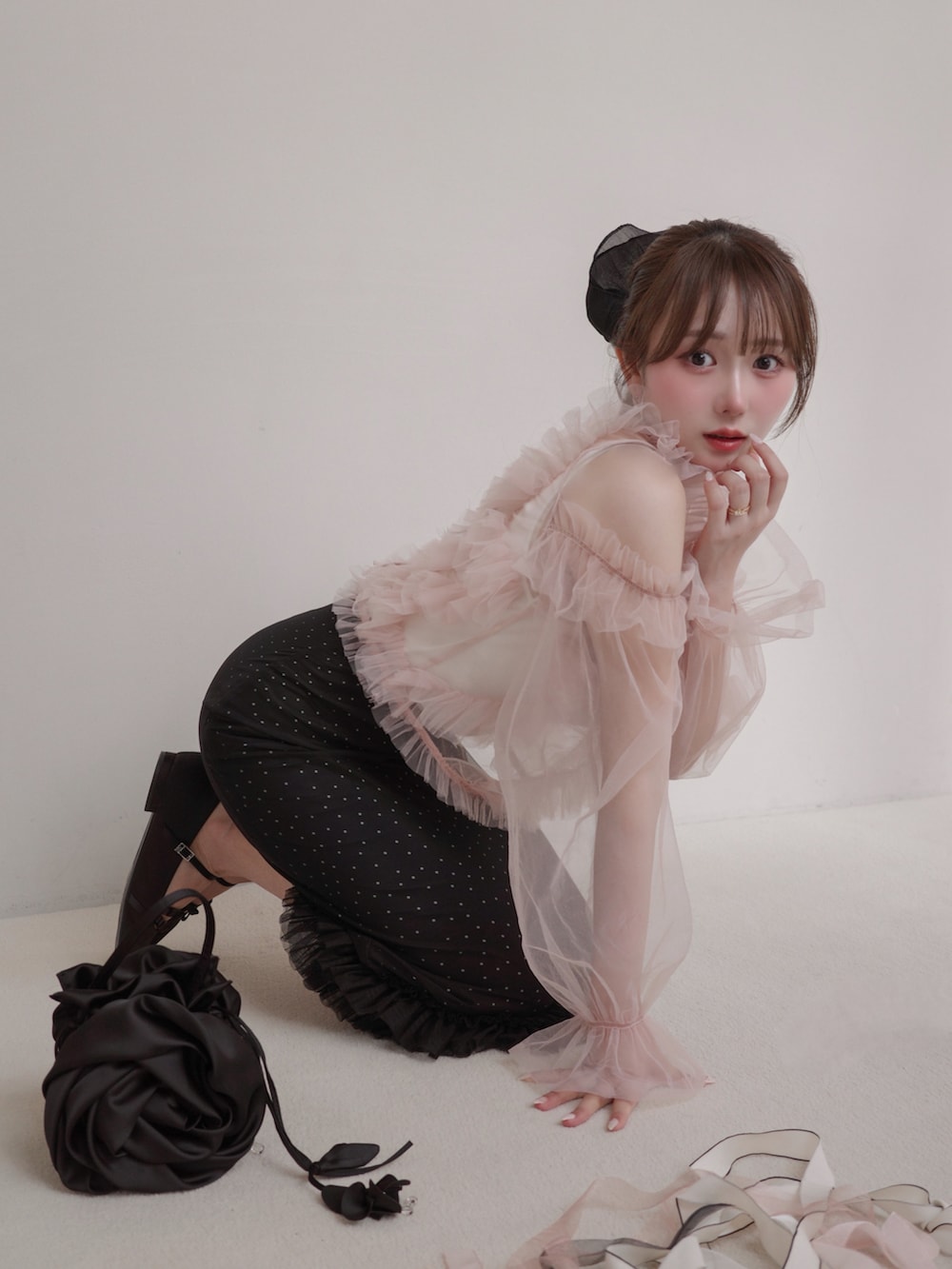 ブラック系のスカート、ピンク系のトップス、ブラック系のハンドバッグを着用したレディースの春コーディネートの2枚目の写真