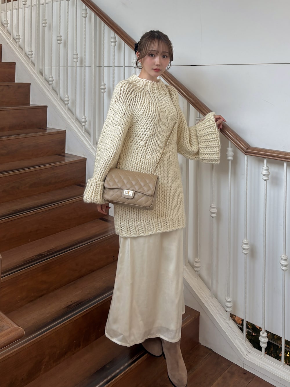 ホワイト系のトップス、ベージュ系のショルダーバッグ、ホワイト系のスカートを着用したレディースの冬コーディネートの2枚目の写真