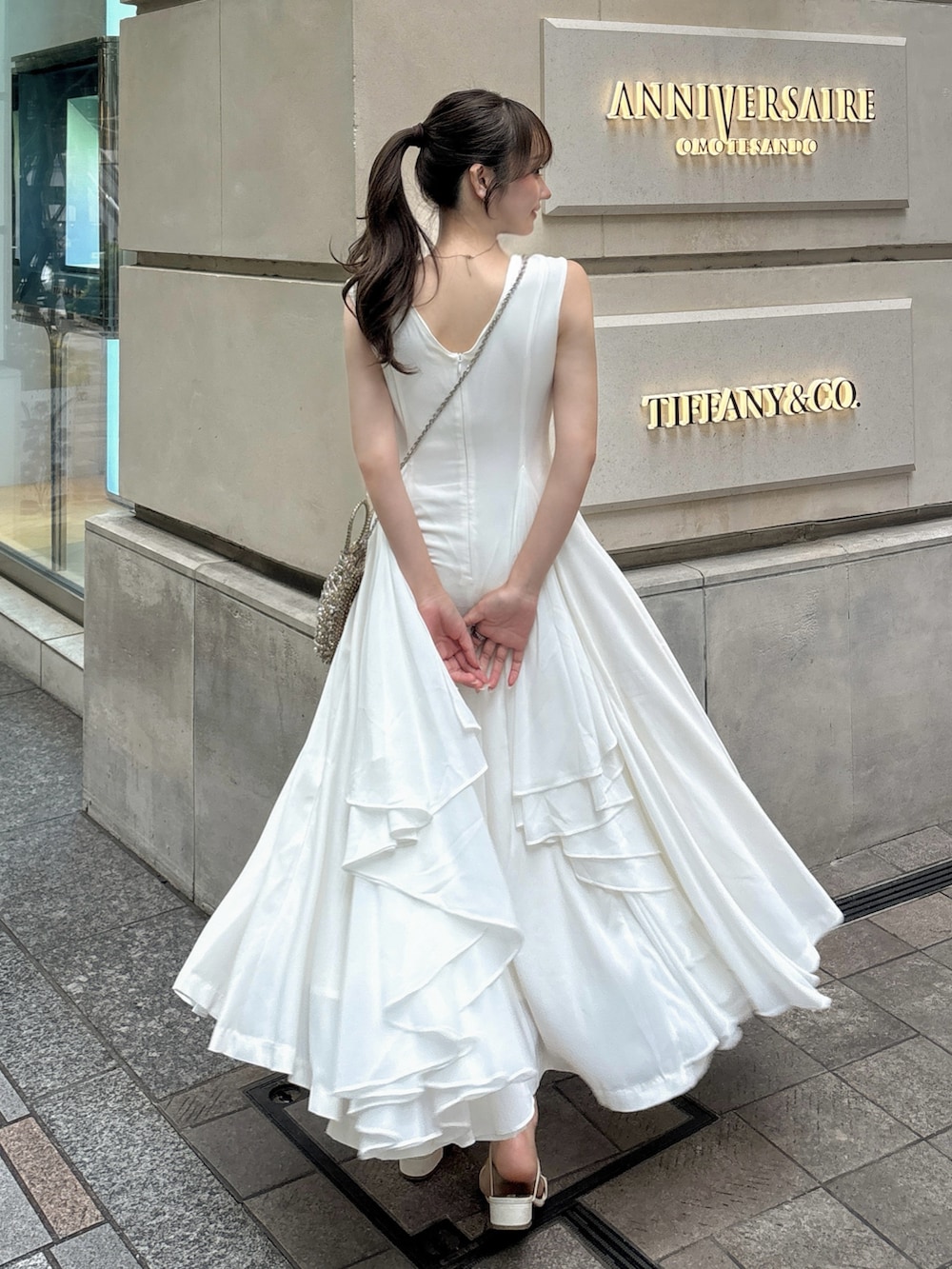 ホワイト系のワンピース/ドレス、ゴールド系のバッグ、ホワイト系のサンダルを着用したレディースの夏コーディネートの3枚目の写真