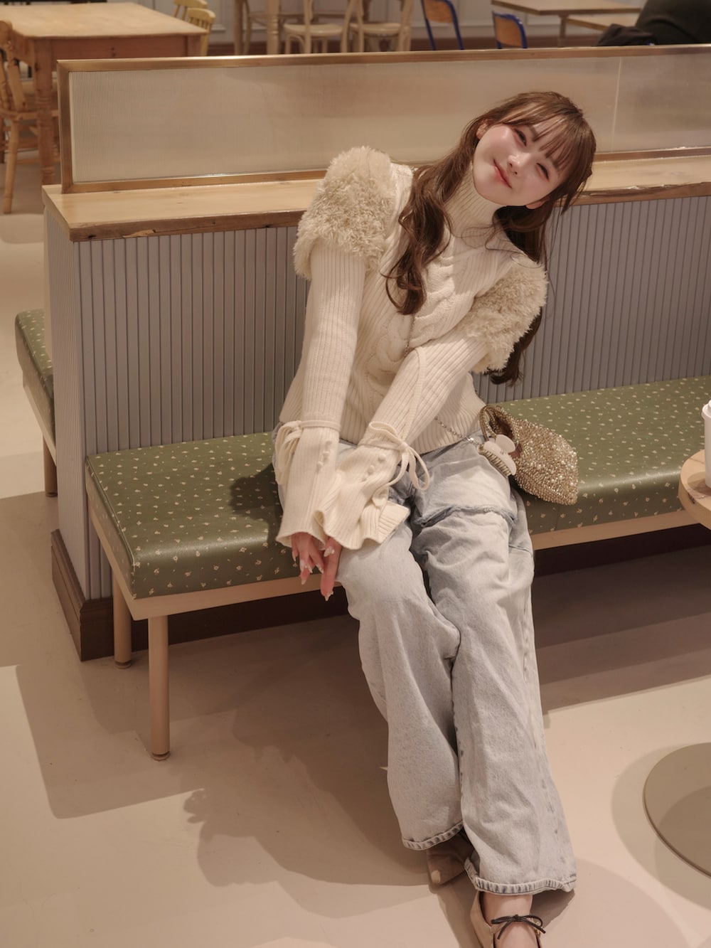 ブルー系のデニムパンツ、ホワイト系のトップス、ゴールド系のバッグを着用したレディースの冬コーディネートの2枚目の写真