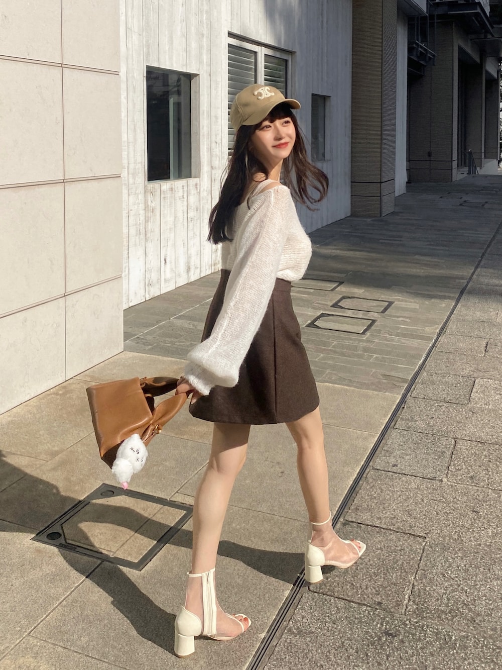 ブラウン系のスカート、ホワイト系のサンダル、ブラウン系のバッグを着用したレディースの秋コーディネートの2枚目の写真