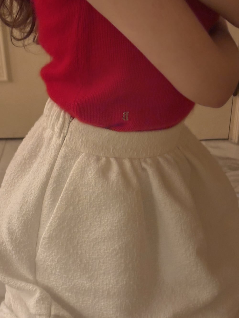 レッド系のトップス、ホワイト系のスカート、ブラウン系のブーツを着用したレディースの冬コーディネートの3枚目の写真