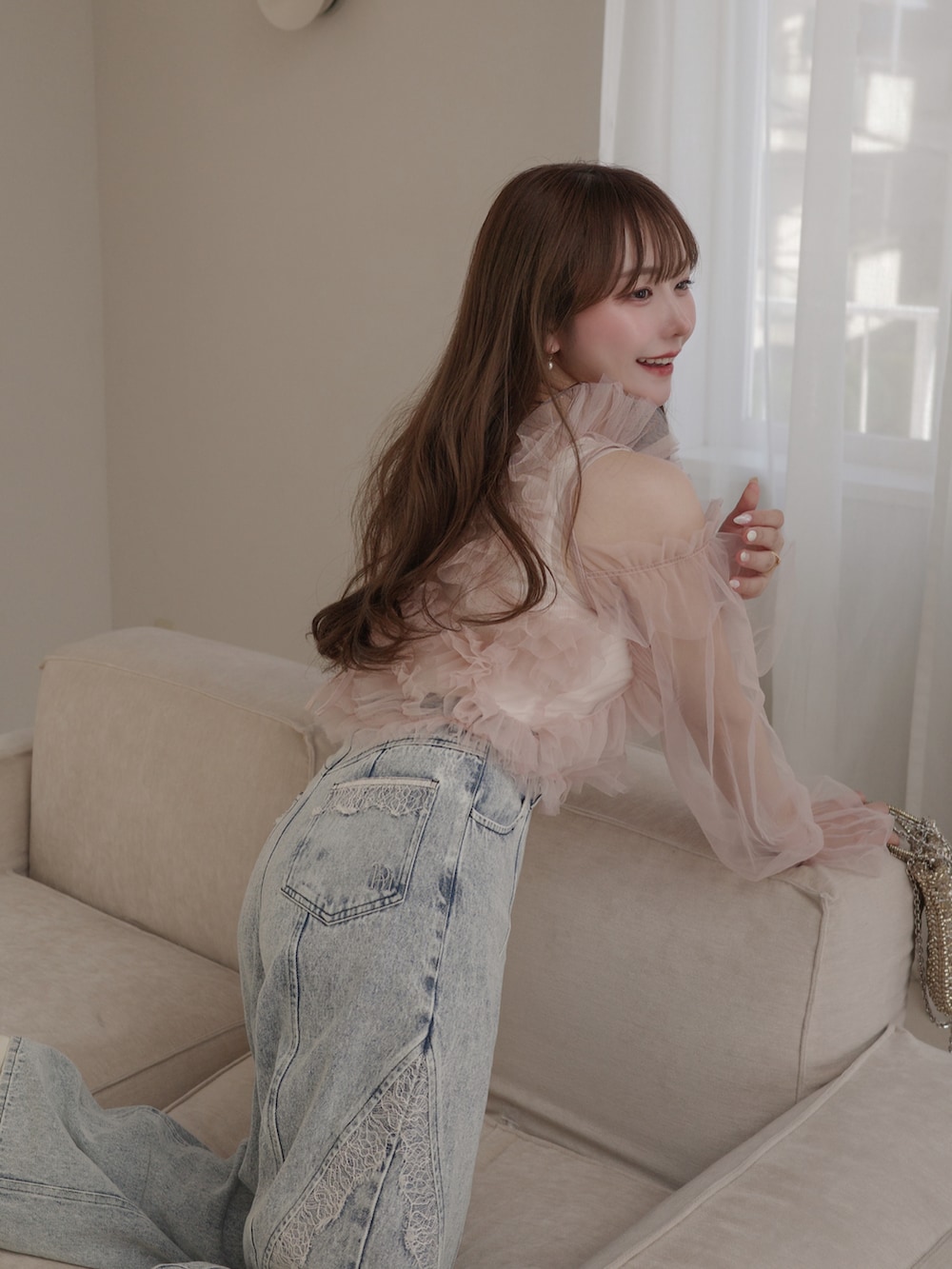 ピンク系のトップス、ゴールド系のバッグ、ブルー系のパンツを着用したレディースの春コーディネートの5枚目の写真